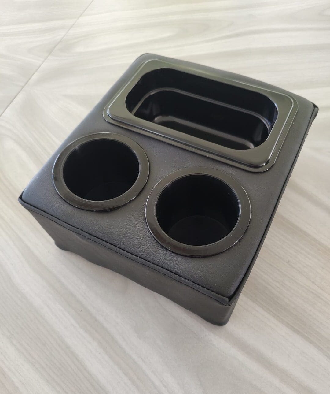 A black plastic cup holder sitting on top of a table.