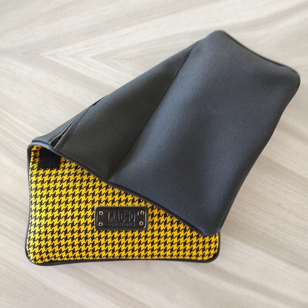 A yellow and black purse sitting on top of a wooden table.